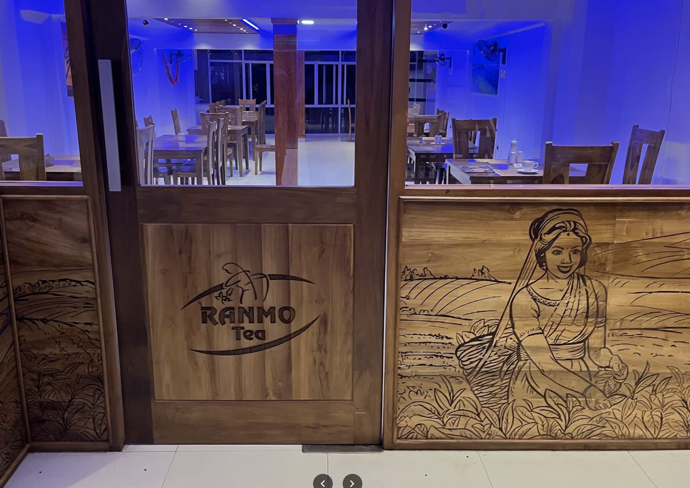 Hand-carved wood entrance mural depicting Sri Lanka's tea country, with the dining room beyond