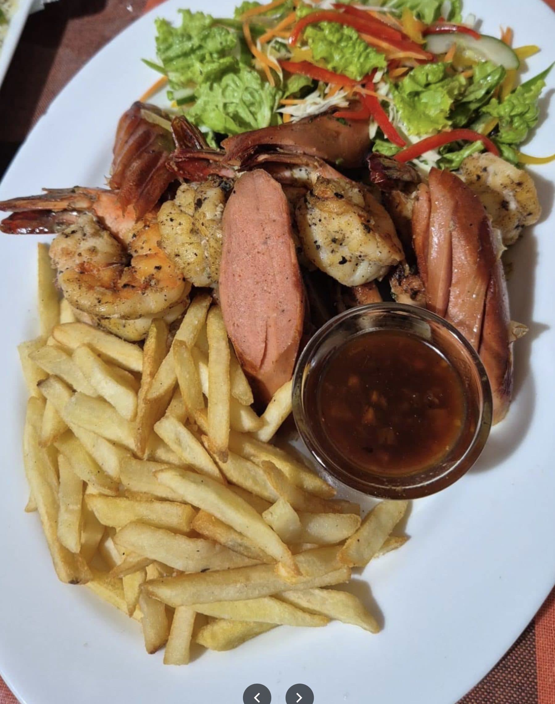 A seafood platter with prawns, sausage and French fries